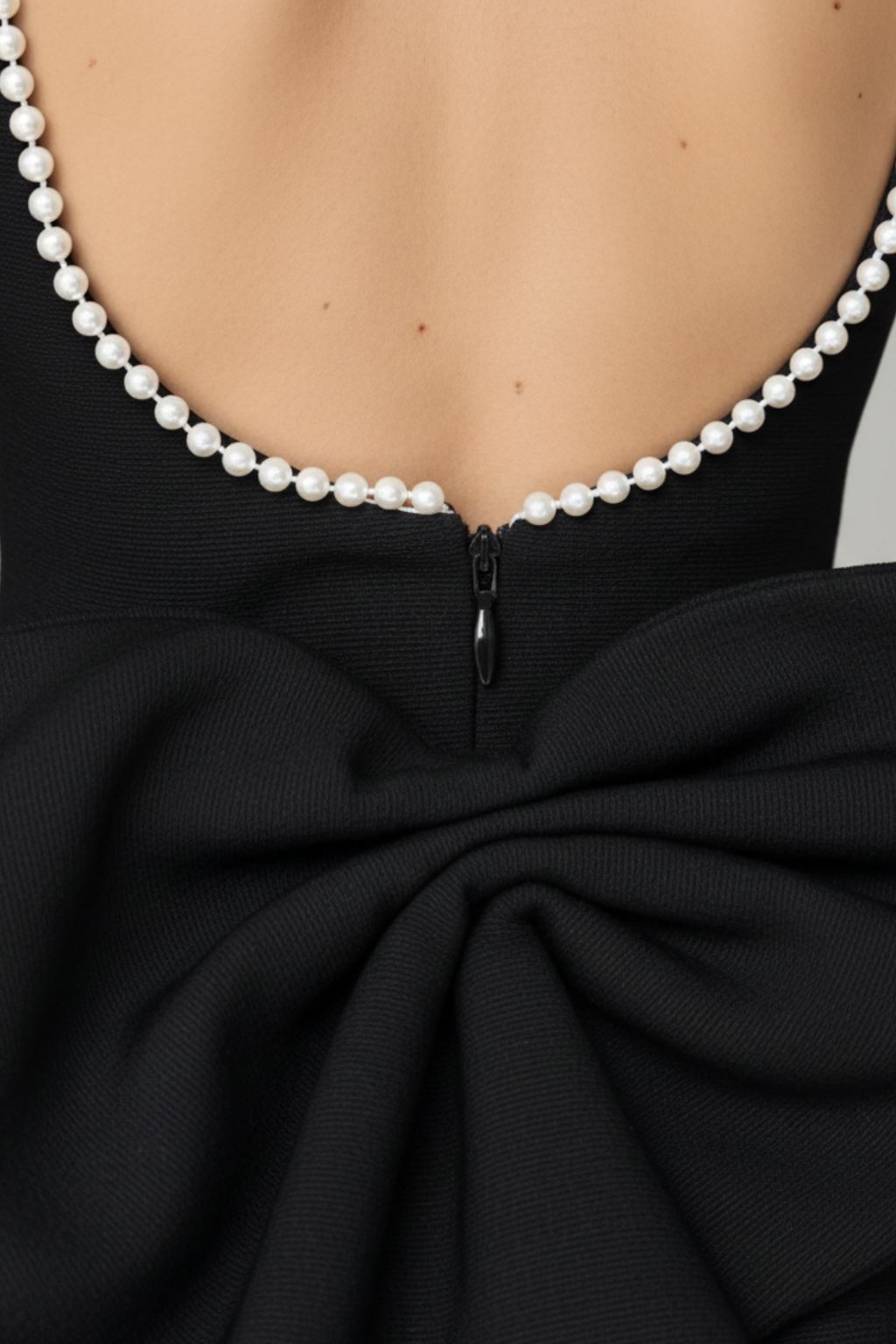Mini abito da donna a schiena scoperta con fiocco di perle che valorizza la figura